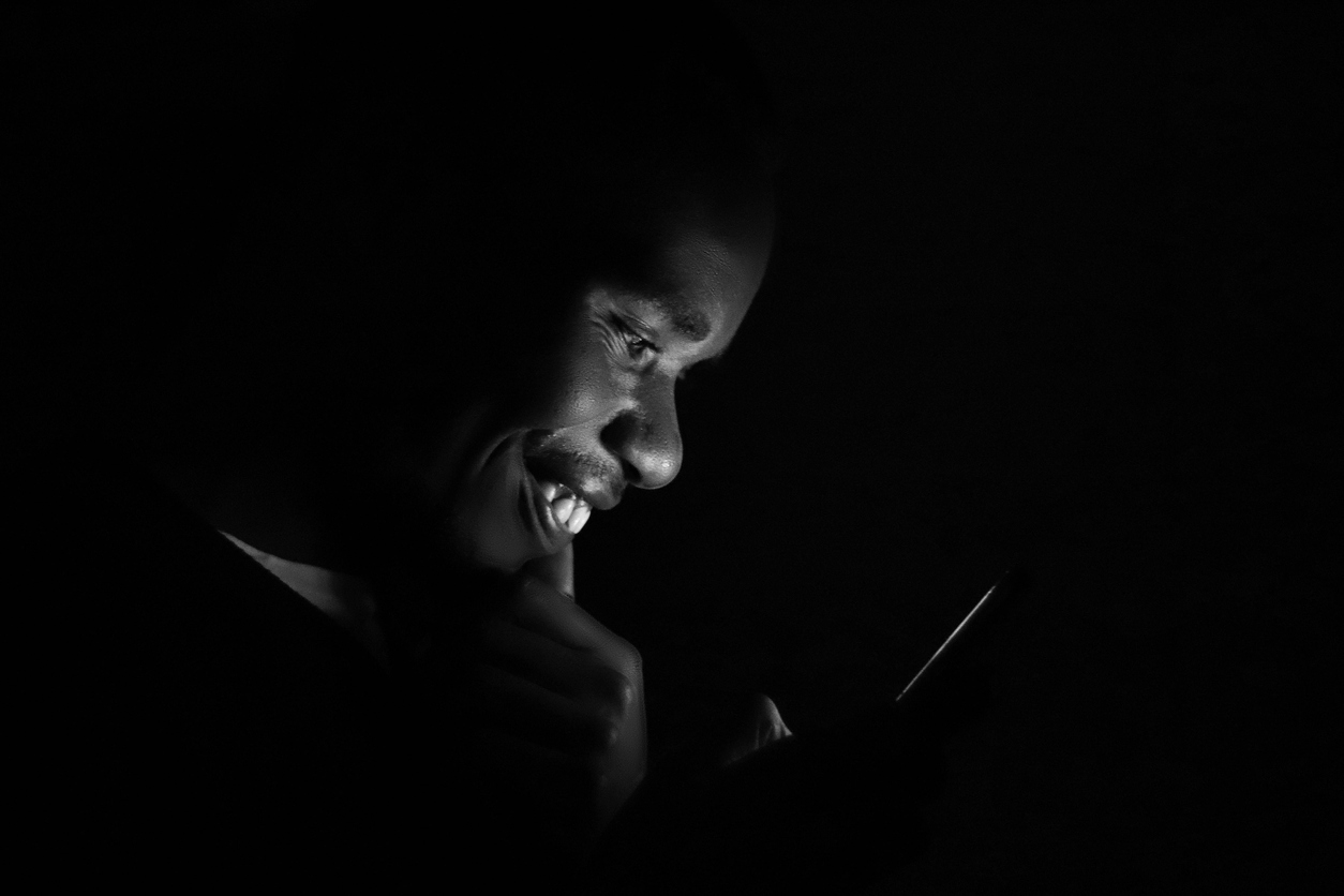 black man smiling at mobile when he finds ILAO